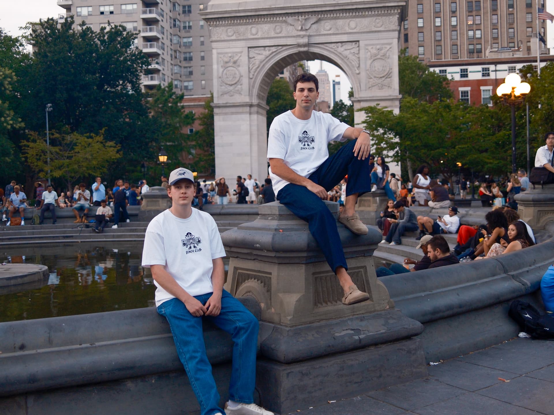 Two men in white Bench Club tees at the Washington Square Park fountain