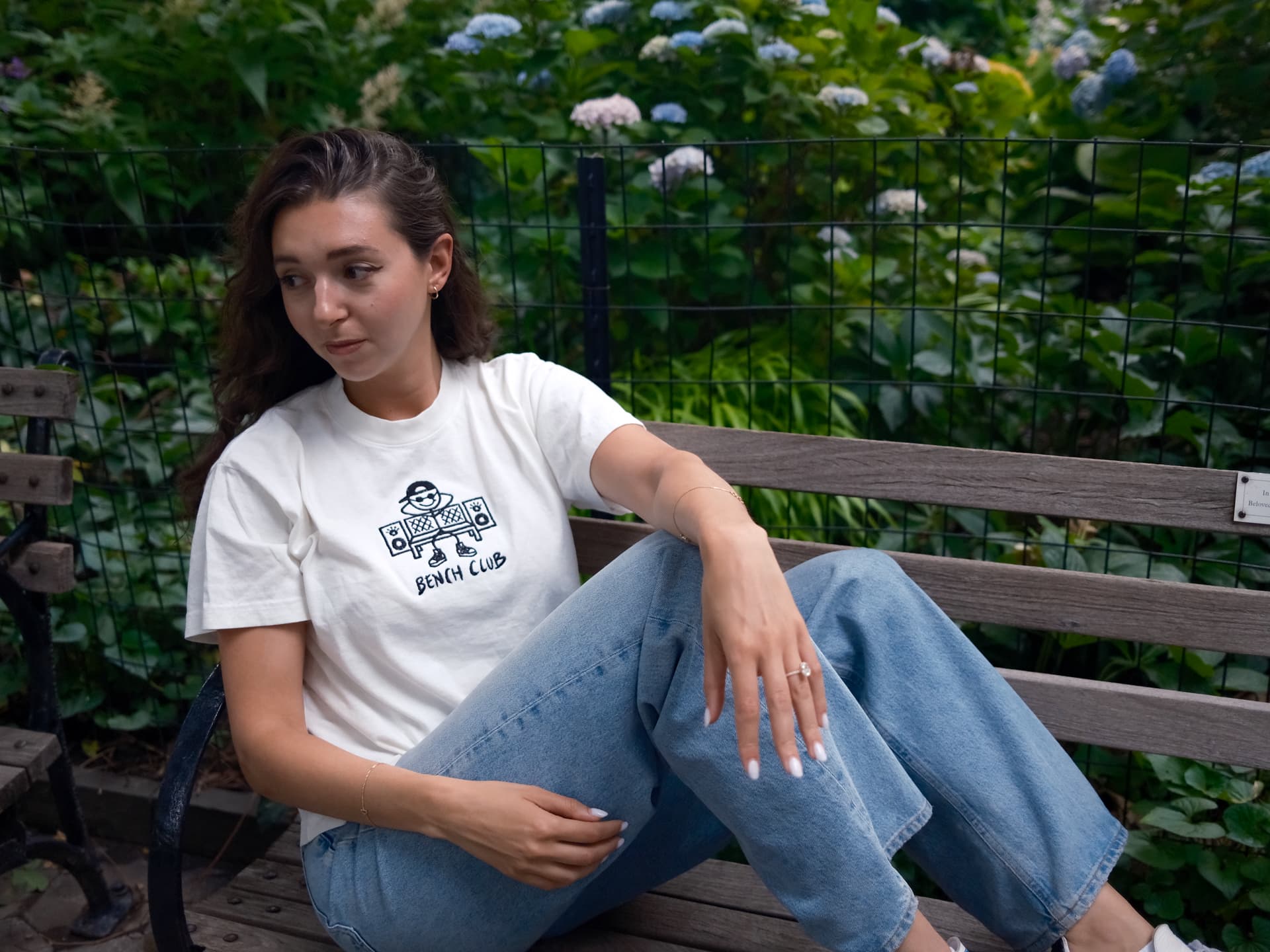 Woman in a white Bench Club tee on a park bench